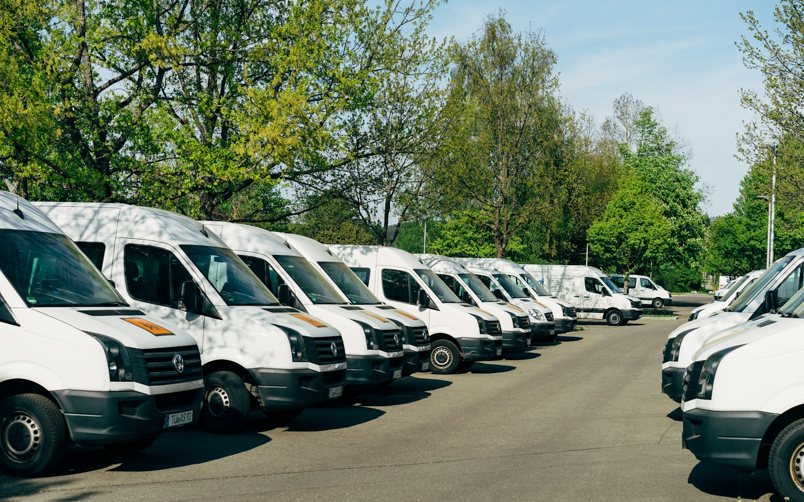 Row of white company vans parked in a fleet lot, the kind of work vehicles a company car crash attorney deals with