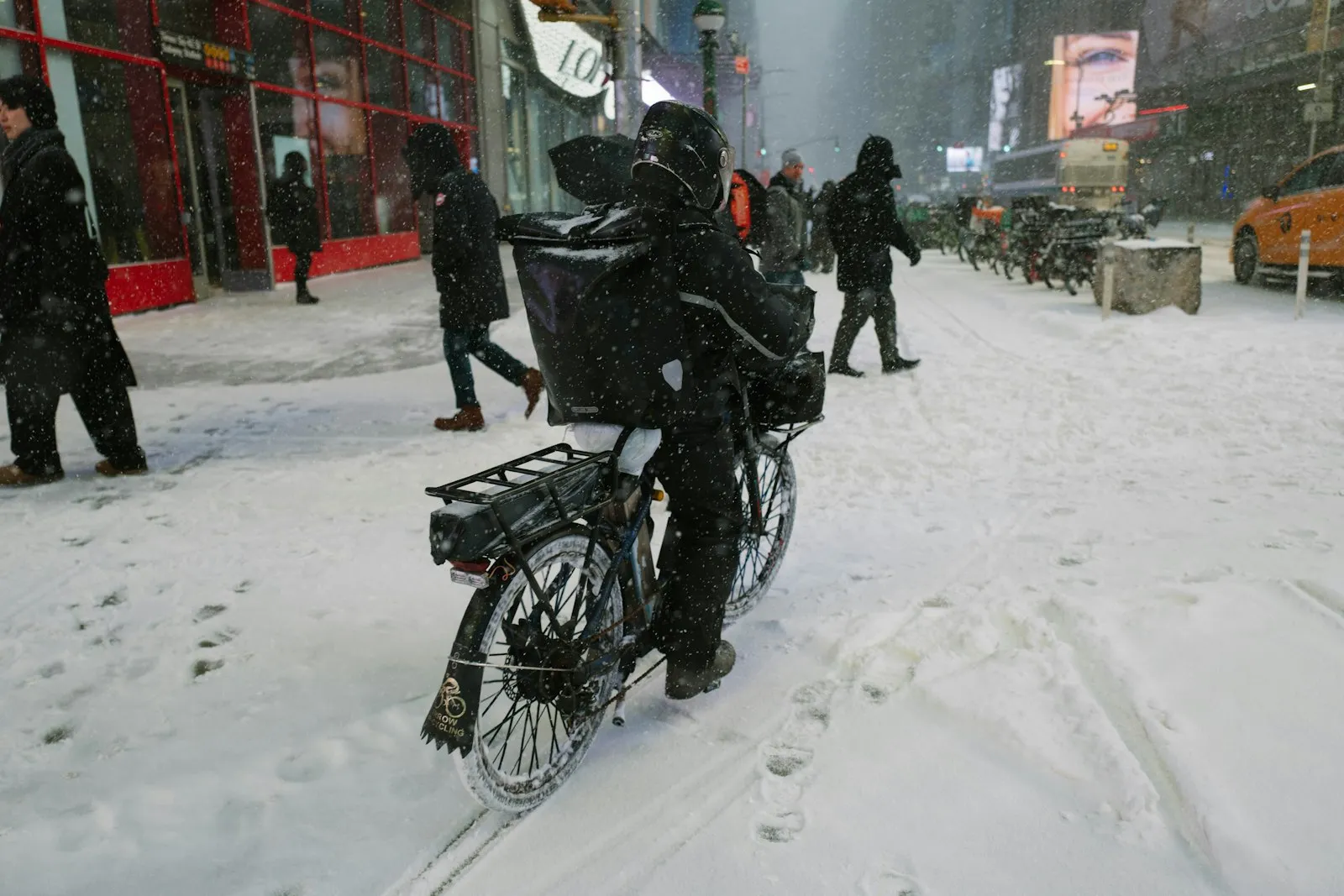 Delivery rider standing with a bike on a snow-covered city street, a situation an E-bike injury lawyer for Maspeth riders sees in winter claims