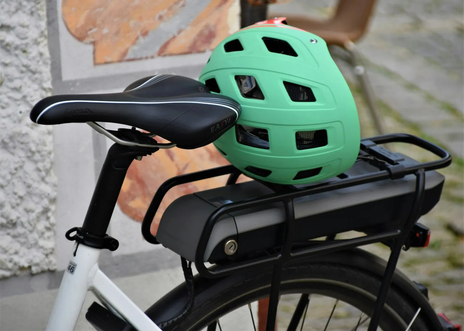 Green helmet resting on the battery of an e-bike rear rack, an item an Electric bike accident lawyer for Maspeth clients asks riders to keep