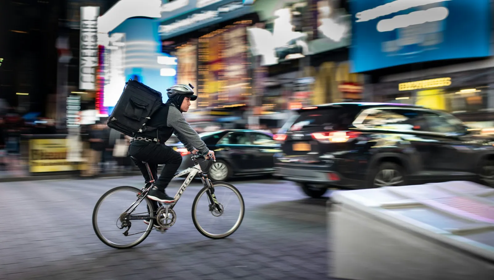 Cyclist with a backpack riding beside cars in heavy traffic, from an e-bike accident attorney page for Utopia