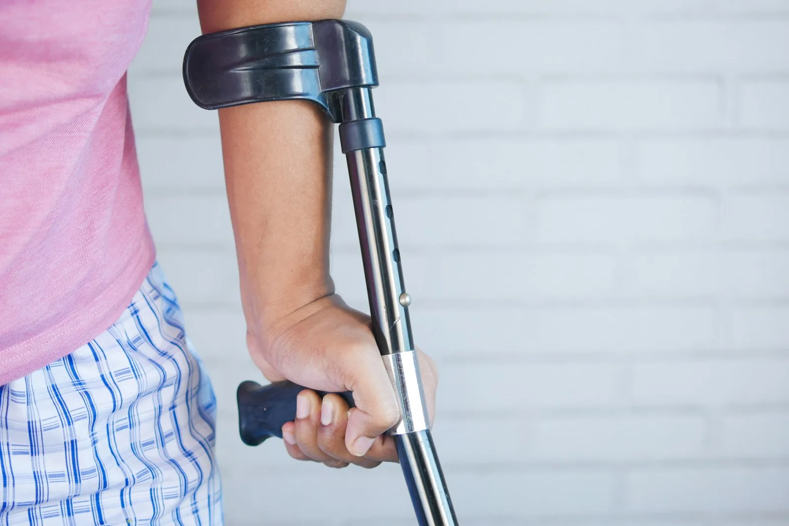 Person standing with a forearm crutch while recovering from an ankle injury, a common situation for a lawyer's client