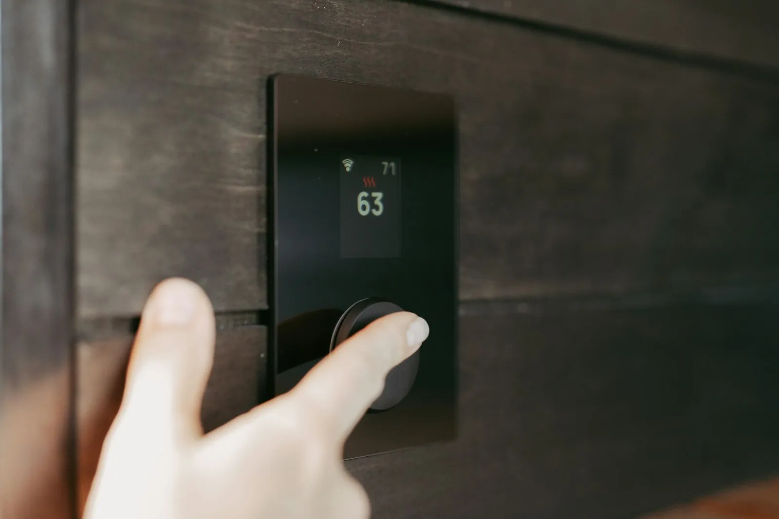 Hand adjusting a wall thermostat as the heat comes on, a moment carbon monoxide attorneys often ask about