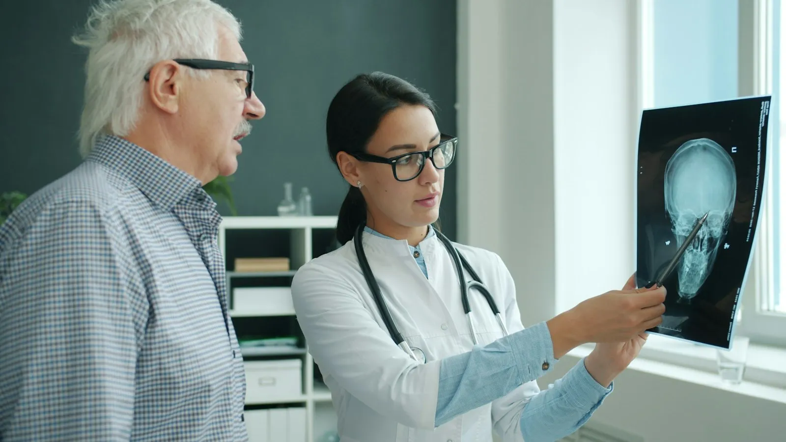 Physician showing a brain scan film to an older male patient, records a concussion attorney may rely on