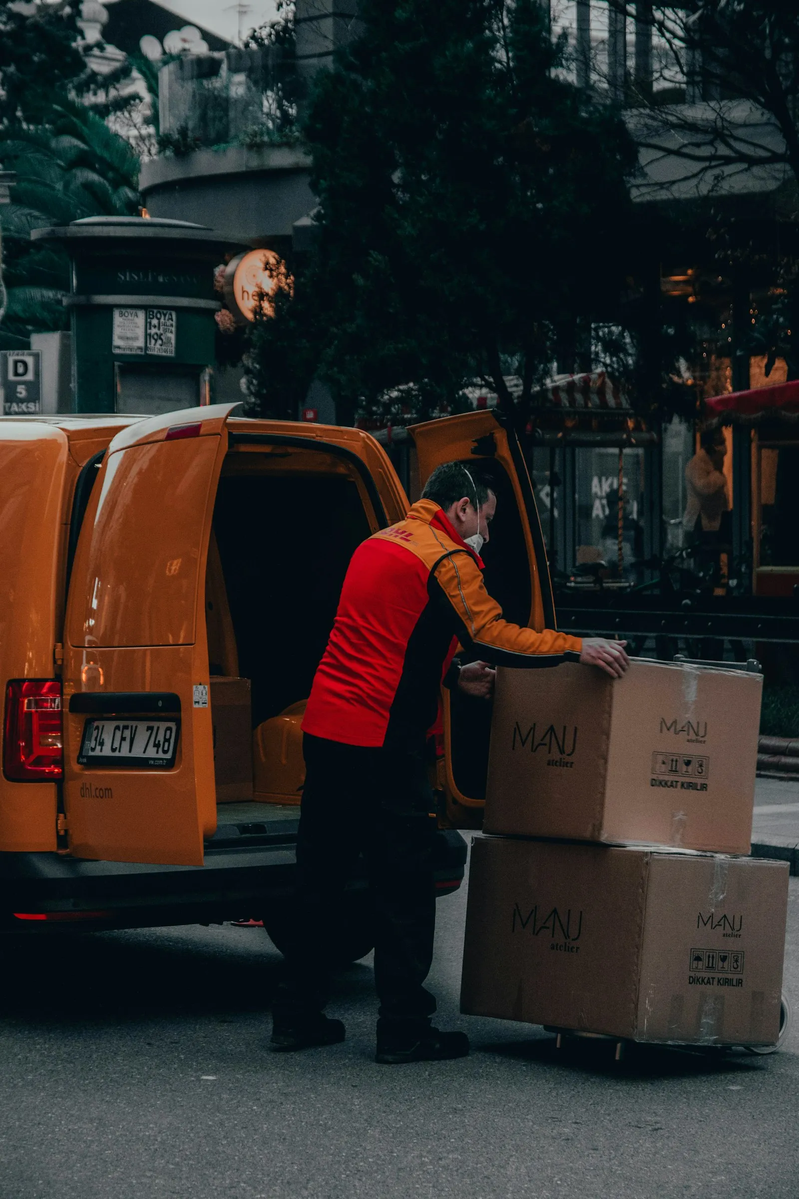 Delivery worker unloading boxes from the back of an orange van at the curb, injury lawyer guide