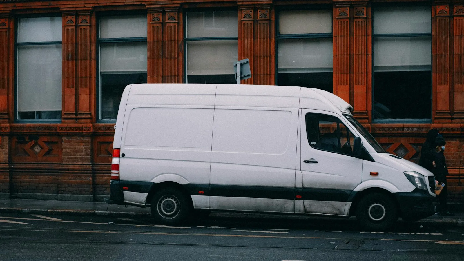 White cargo van parked beside a brick building, delivery van accident attorney article