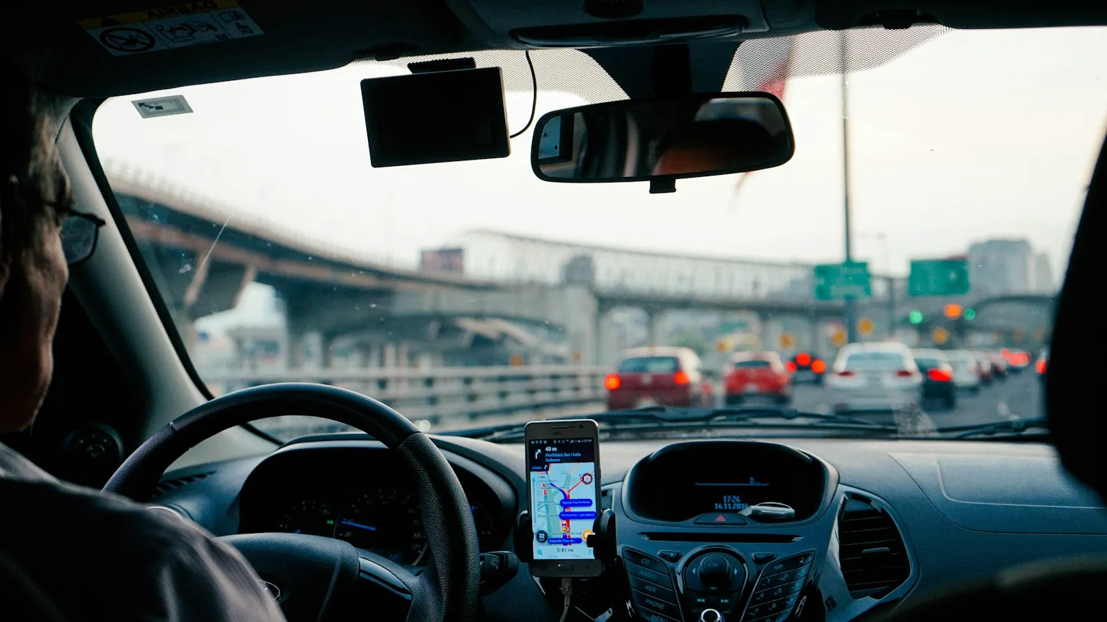 Vista desde el asiento del conductor con un teléfono montado en el panel de instrumentos en tráfico de carretera, el enfoque de un abogado de conducción distraída