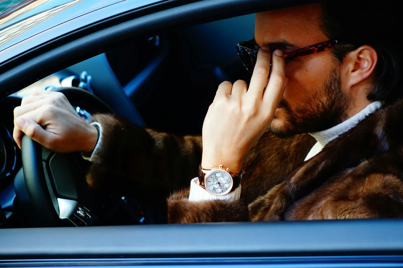 Driver rubbing his eyes under his glasses while holding the wheel, a warning sign a drowsy driving attorney looks for