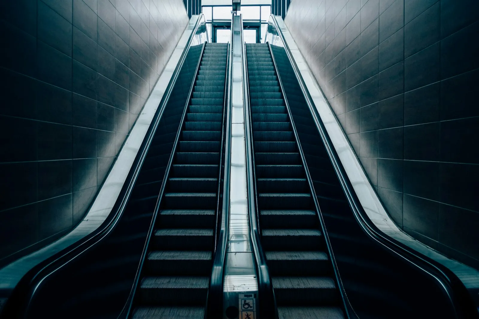 Pair of escalators rising through a dimly lit station corridor, illustrating escalator injury claims handled by a lawyer