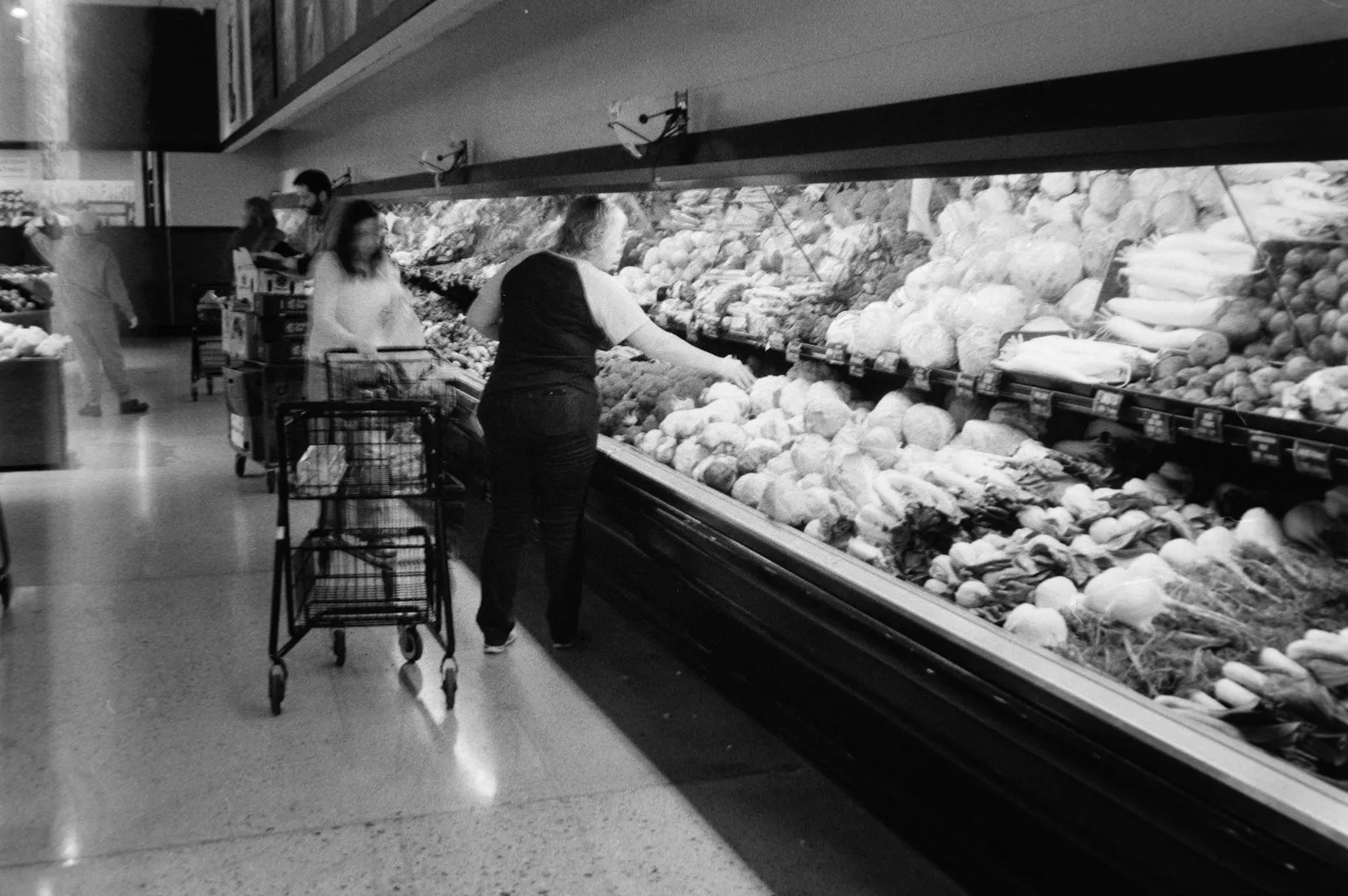 Shopper pushing a cart through a produce section where a grocery store slip and fall attorney looks for dropped fruit