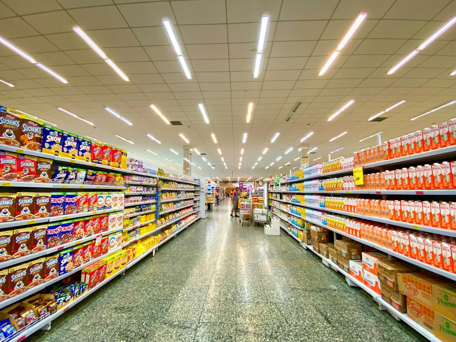 Long, brightly lit grocery store aisle with stocked shelves, the kind of setting a slip and fall lawyer examines