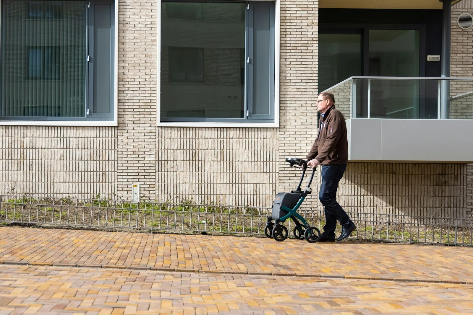 Older man walking with a rolling walker on a sidewalk, a hip recovery a hip injury attorney may document