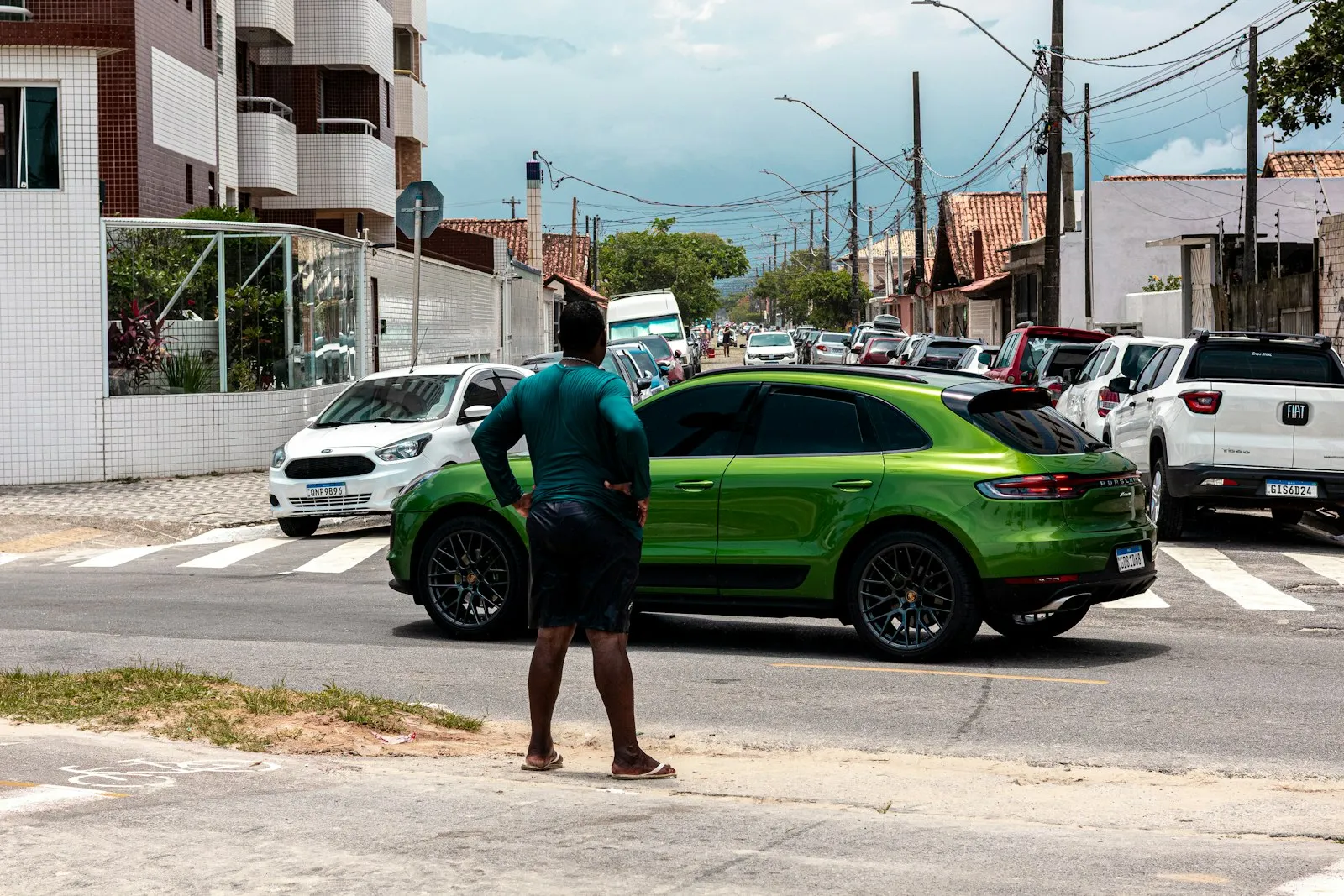 Man waiting at a street corner as cars pass through an intersection, for an intersection accident lawyer article on crosswalks