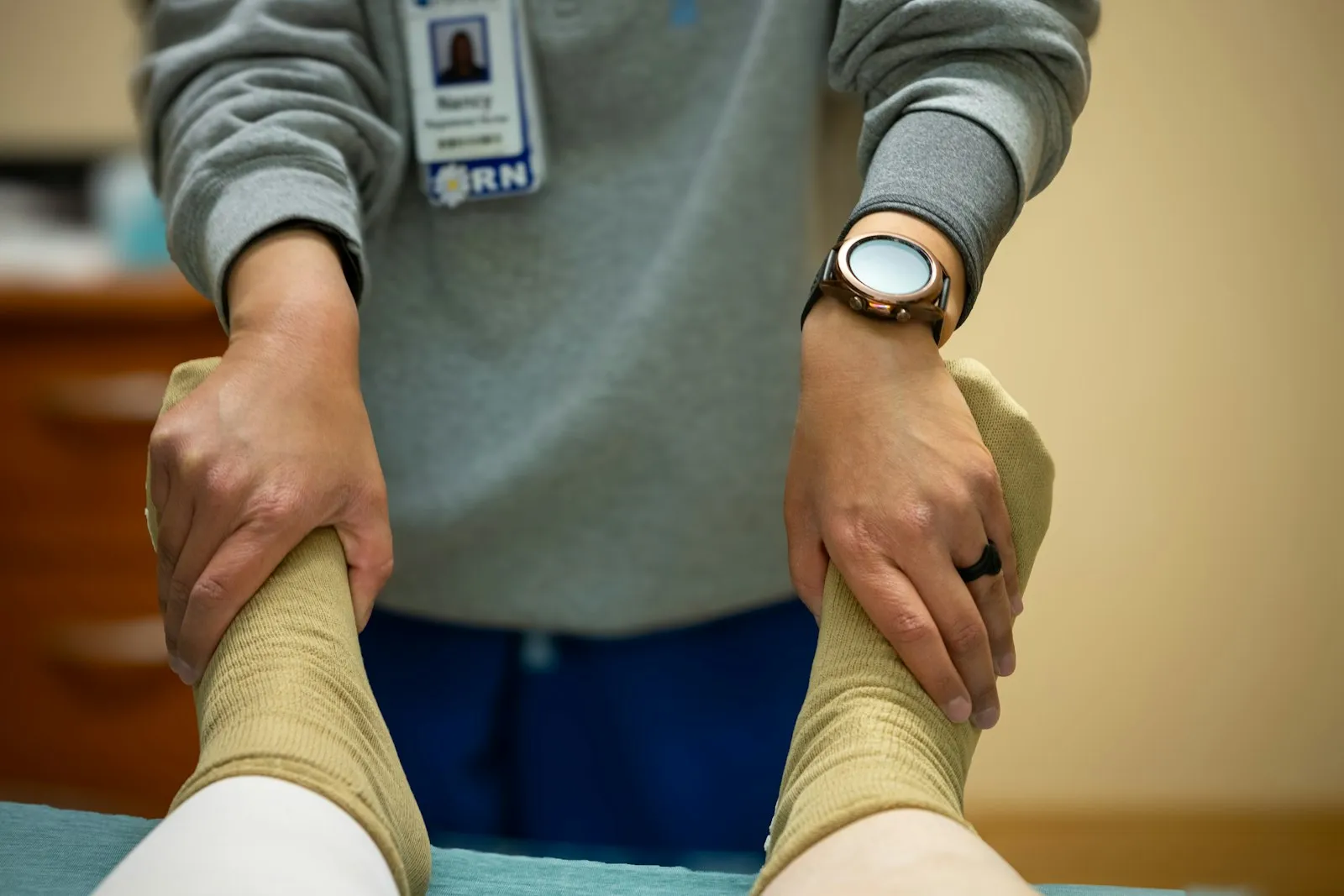 Les mains d'un clinicien soutenant la jambe inférieure bandée d'un patient après une blessure au genou, tel qu'examiné par un avocat