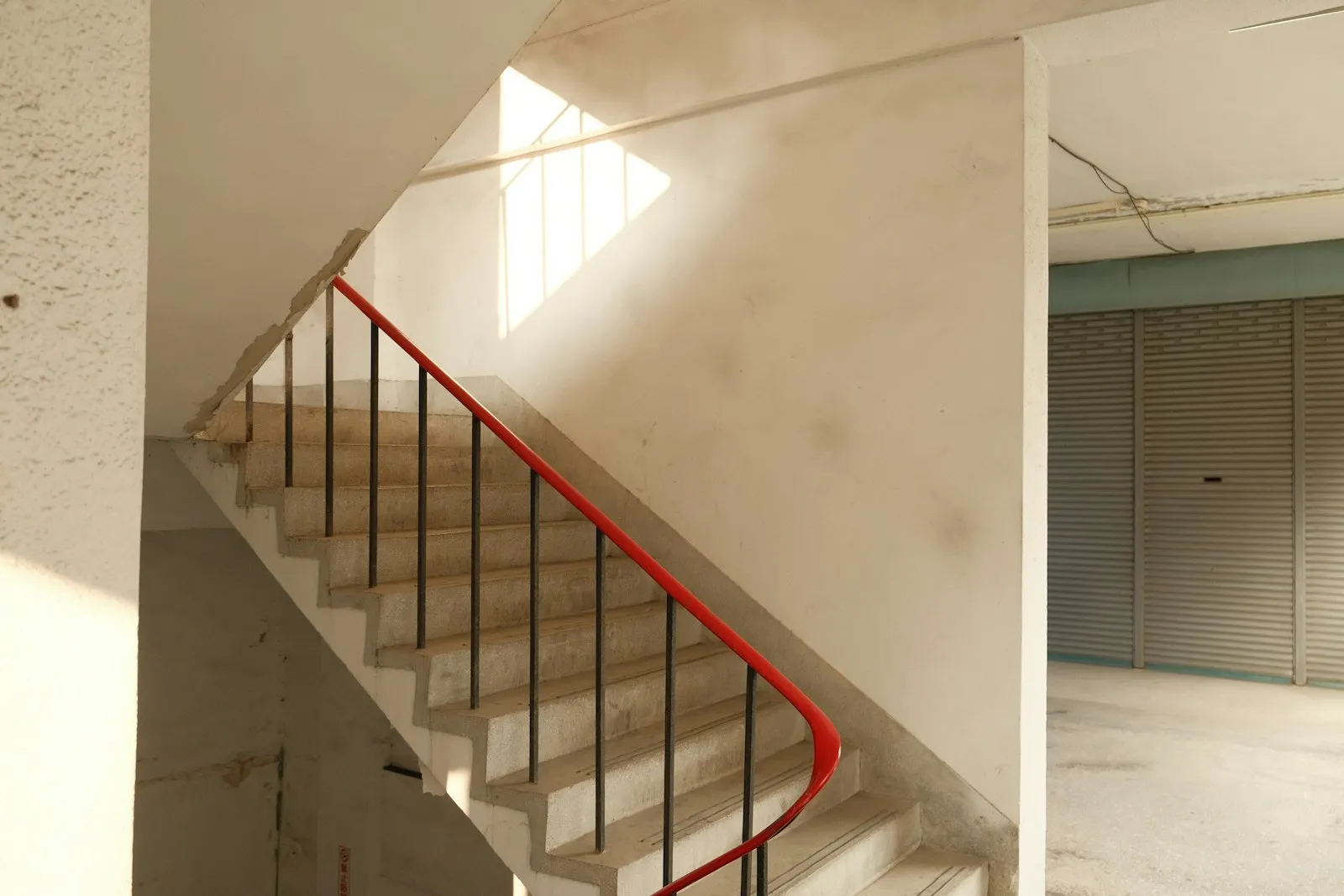 Concrete apartment stairwell with a red handrail, a common landlord negligence lawyer case setting