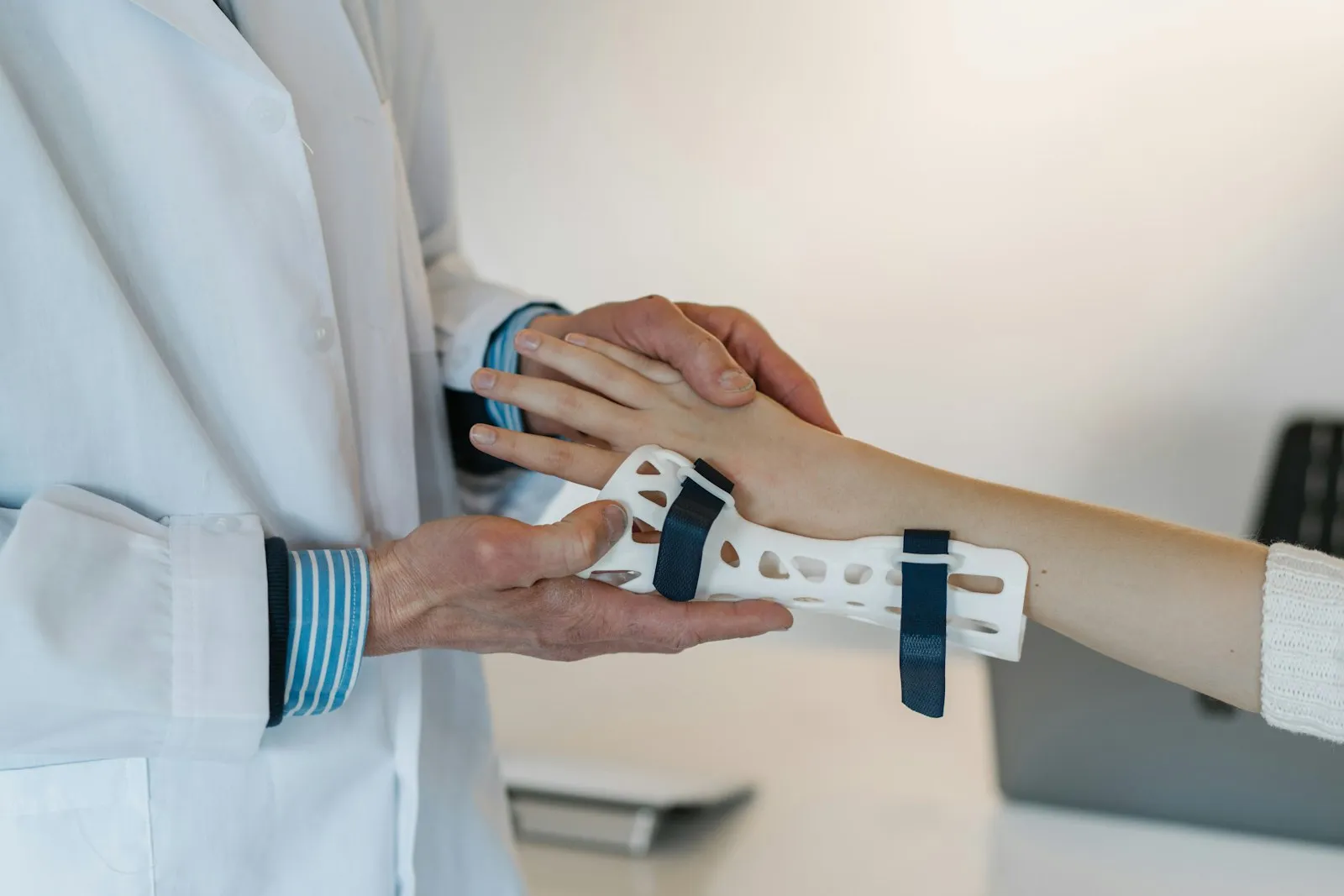 Doctor fitting a white wrist brace on a patient's forearm after a nerve injury, as reviewed by a nerve damage attorney