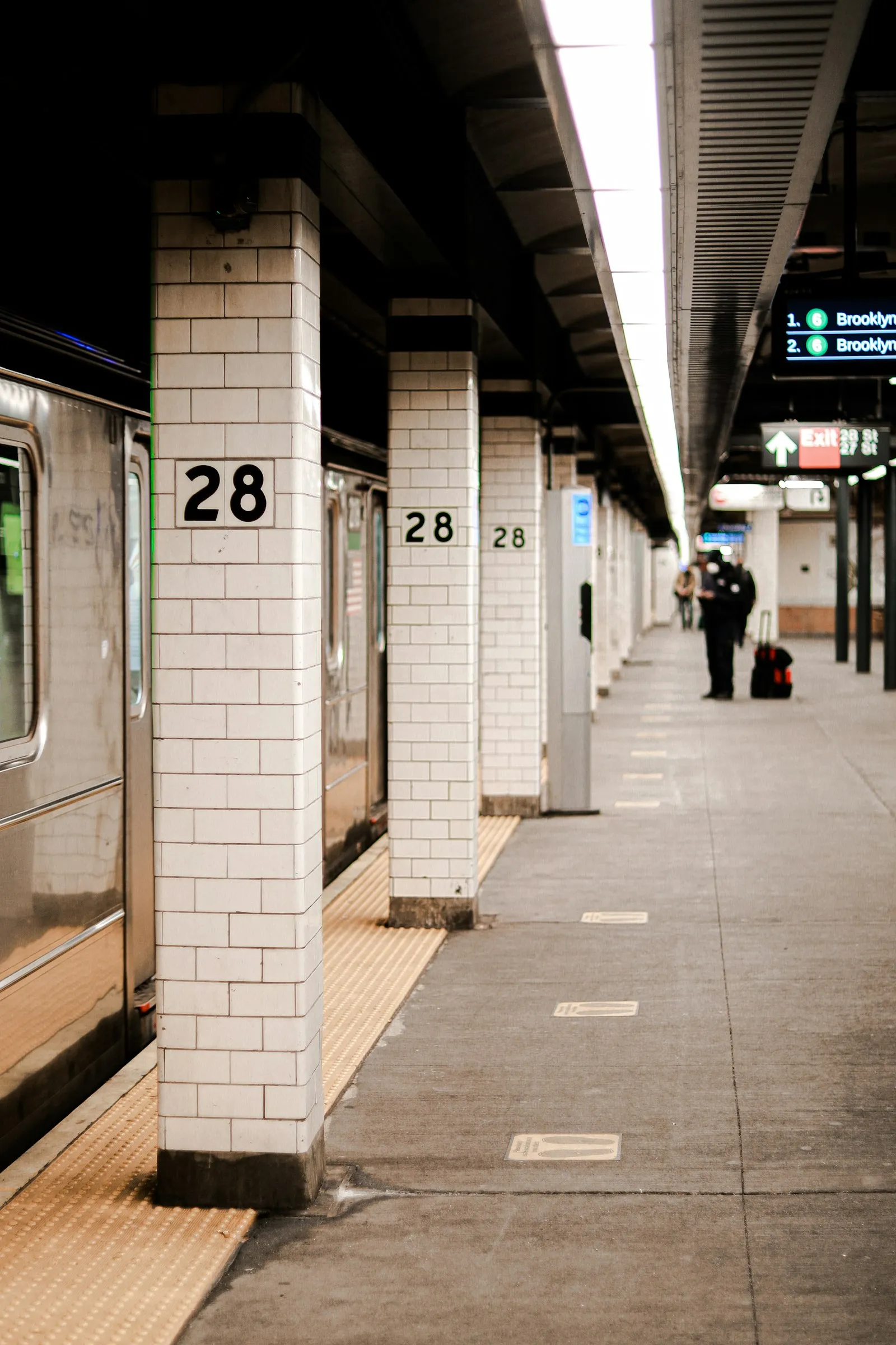 MTA accident lawyer: tiled New York City subway platform with support columns and a rider waiting