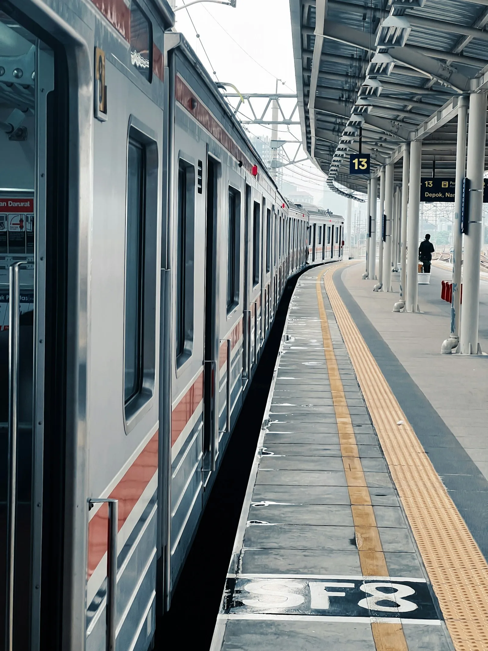 Commuter train stopped at an outdoor station platform, for a Queens Village pedestrian accident lawyer guide