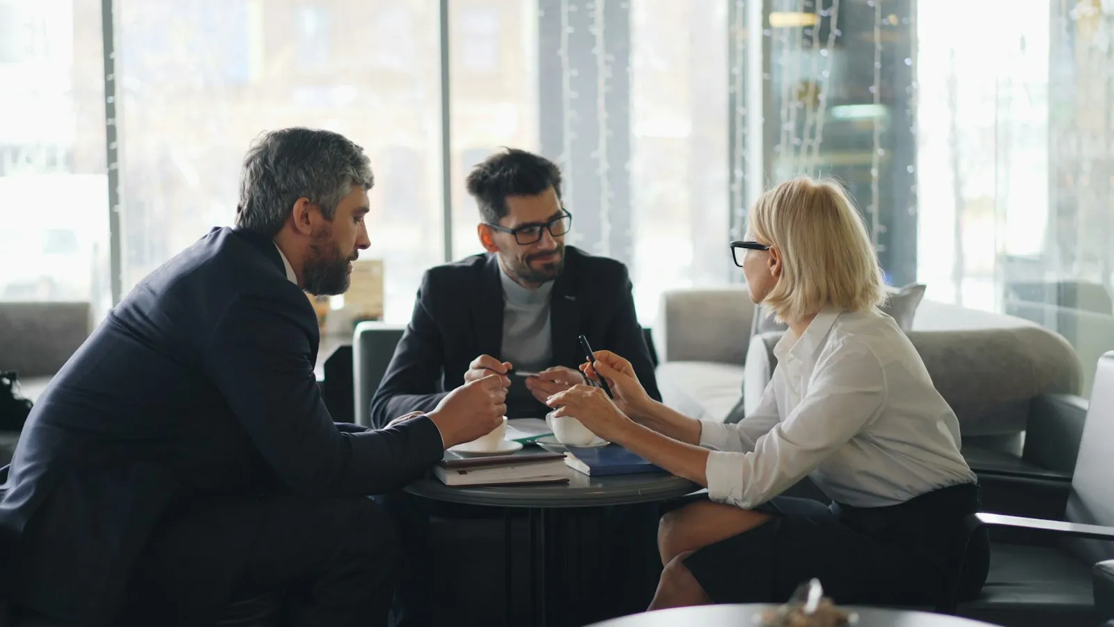 Abogado reunido con dos clientes en una mesa en una oficina brillante, representando una consulta de abogado de lesiones personales de Cambria Heights