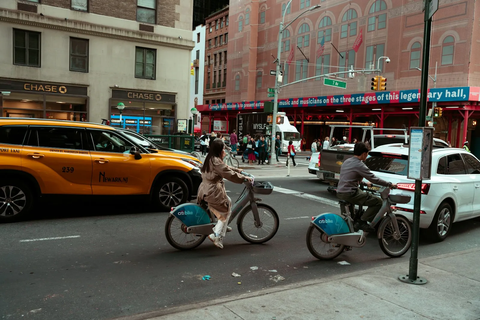Two people riding bikes down a city street
