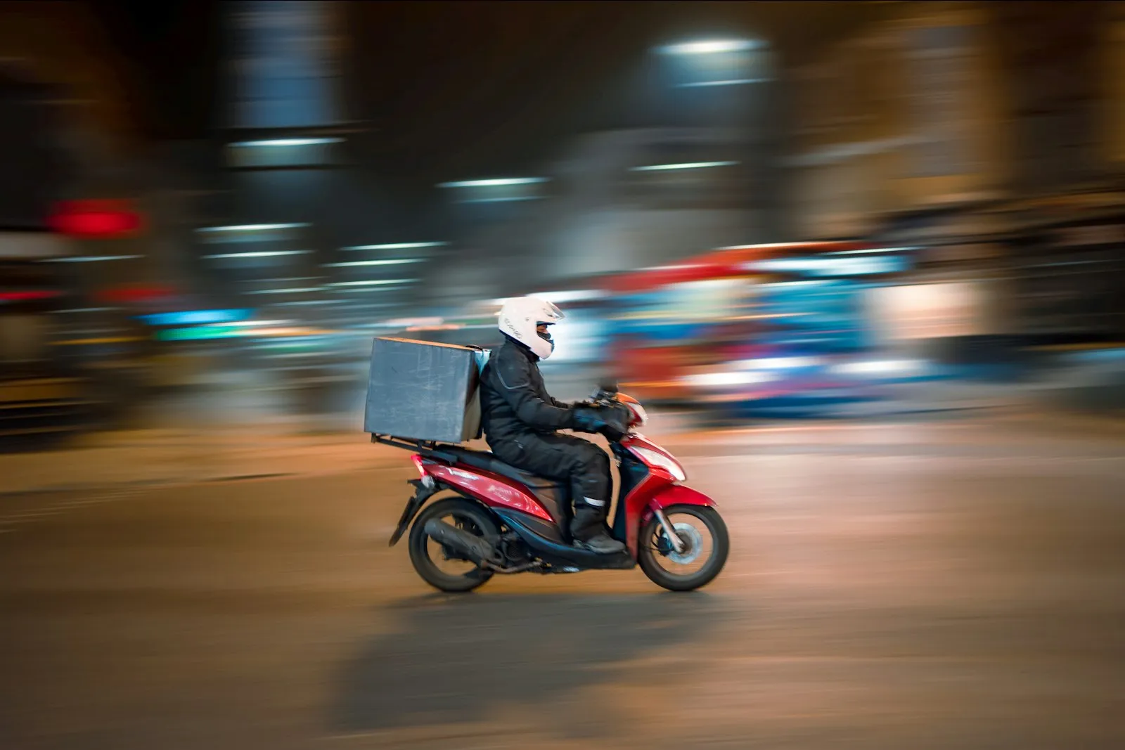 Delivery rider on a red scooter in city traffic