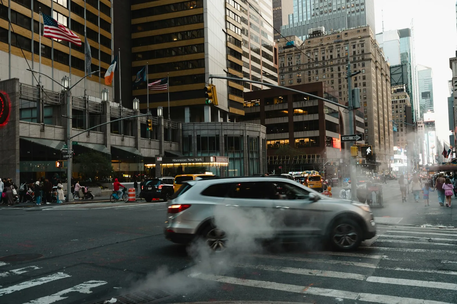 Car driving down a city street lined with tall buildings