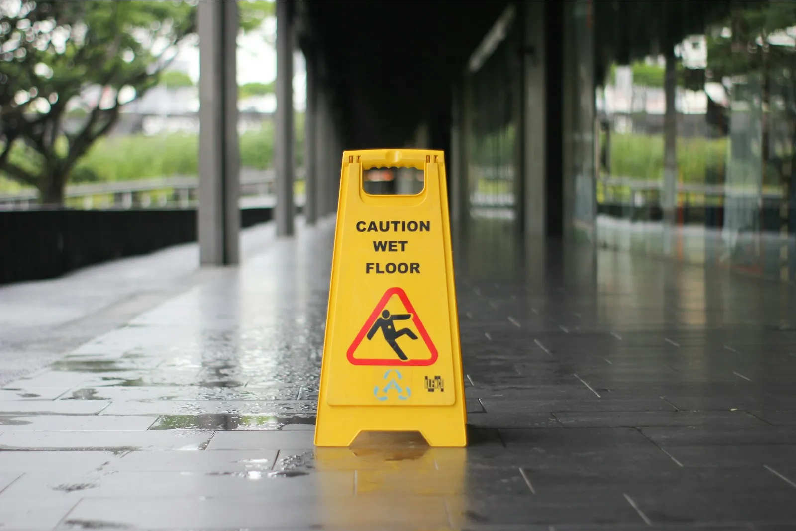 Yellow caution wet floor sign on wet pavement