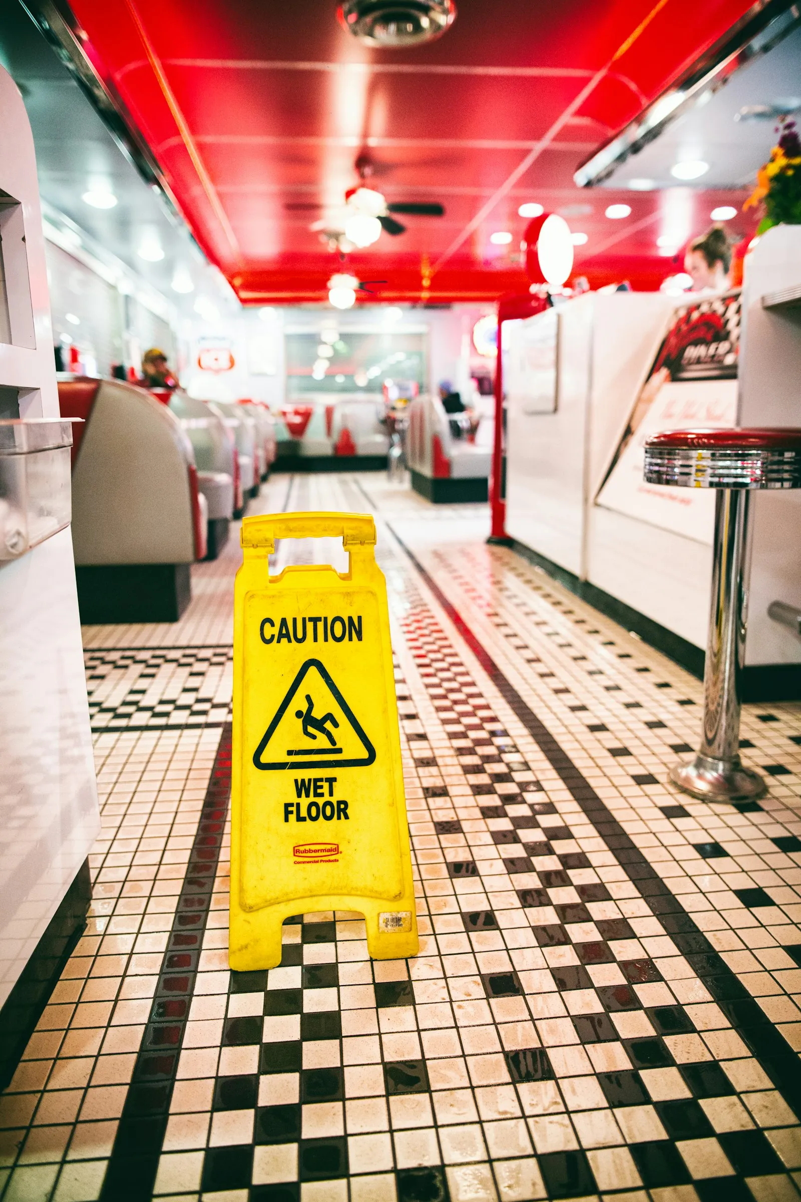 Yellow caution wet floor sign on checkered diner tile, from a restaurant slip and fall attorney article