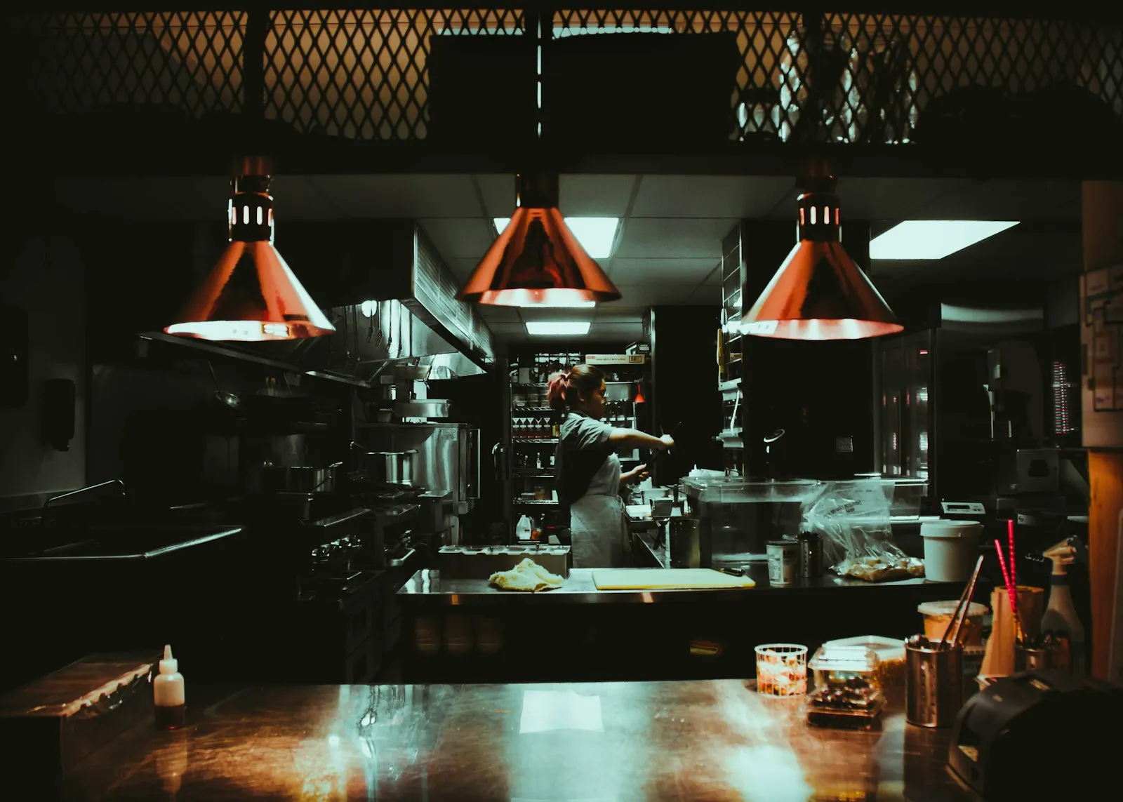 Dim commercial restaurant kitchen with hanging heat lamps, related to a restaurant injury lawyer guide