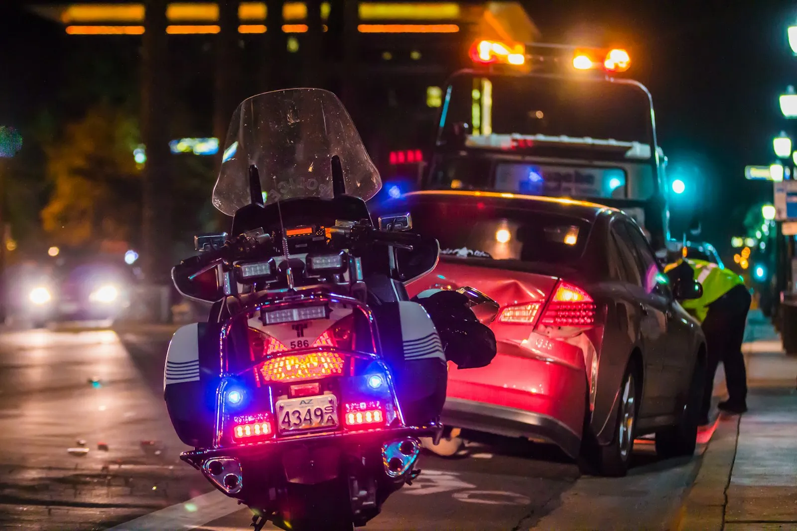 Police motorcycle with flashing lights stopped beside a car at night after a road rage incident handled by an attorney