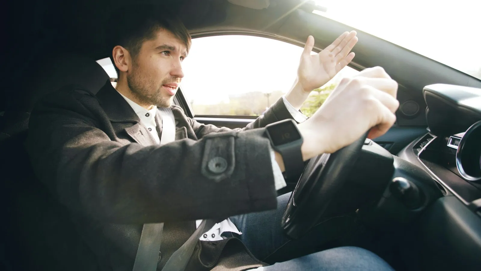 Angry man in a suit gesturing while gripping the steering wheel, illustrating a road rage accident lawyer case
