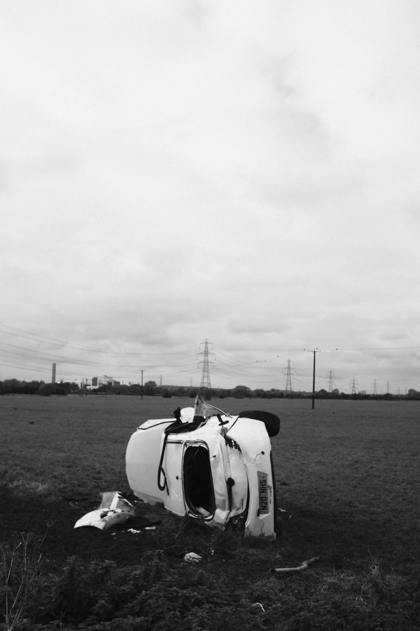 Overturned white car lying on its roof in a grassy field, a rollover case for an attorney to reconstruct