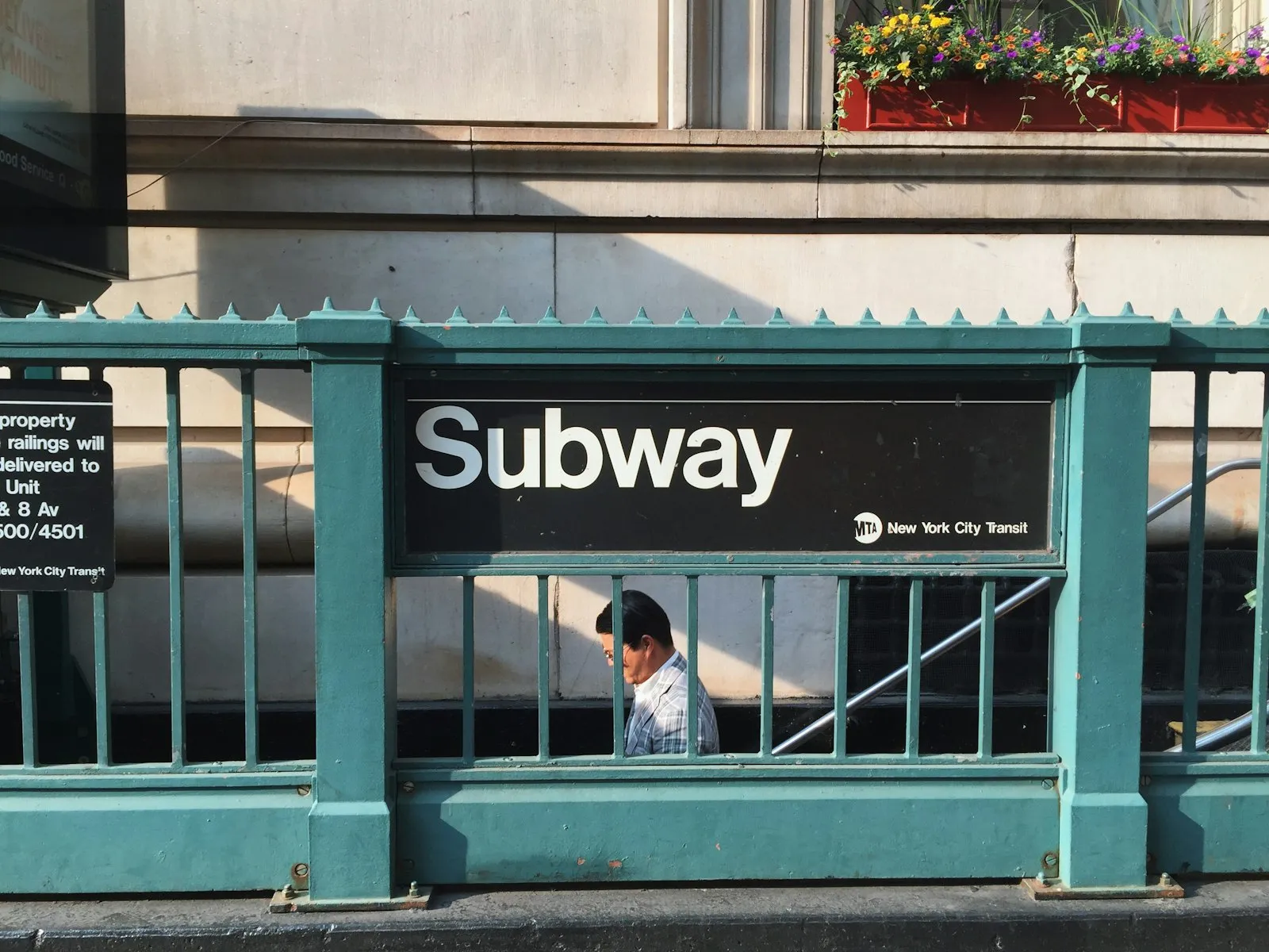 Subway accident lawyer NYC: green New York City subway entrance railing with a Subway sign