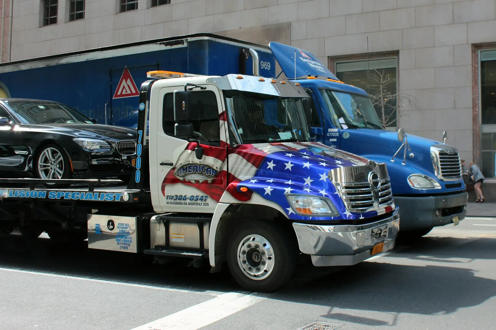 Tow truck with a car loaded on its flatbed parked at a city curb, relevant to a tow accident lawyer investigation