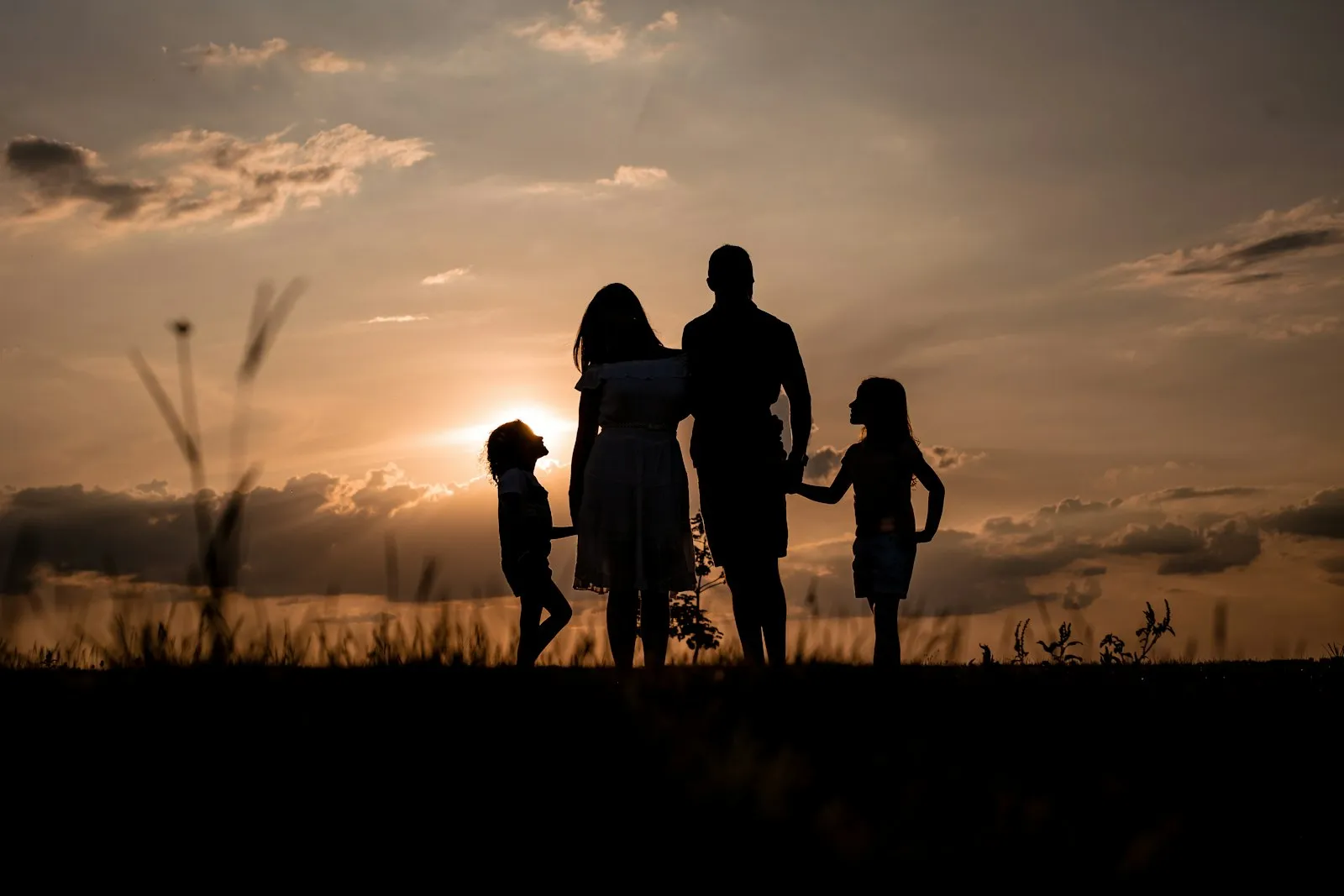 Wrongful death attorney Queens: silhouette of a family holding hands at sunset